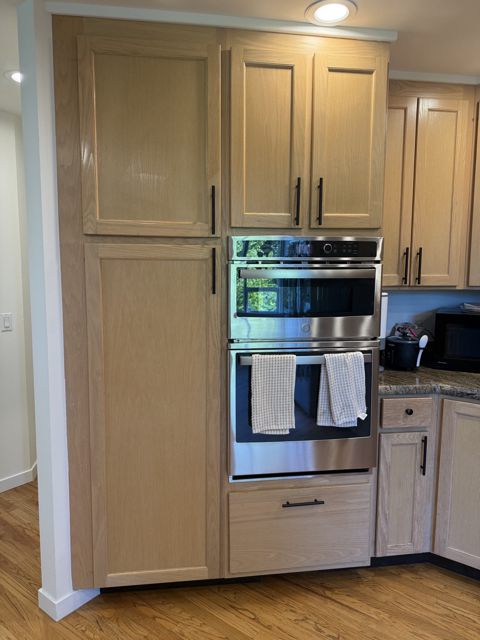 Tall pantry cabinet next to built-in wall ovens
